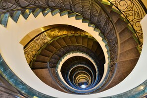 A spiral staircase with ornate metal railings and a mirrored wall. - Warwick Ankara (Ankara)