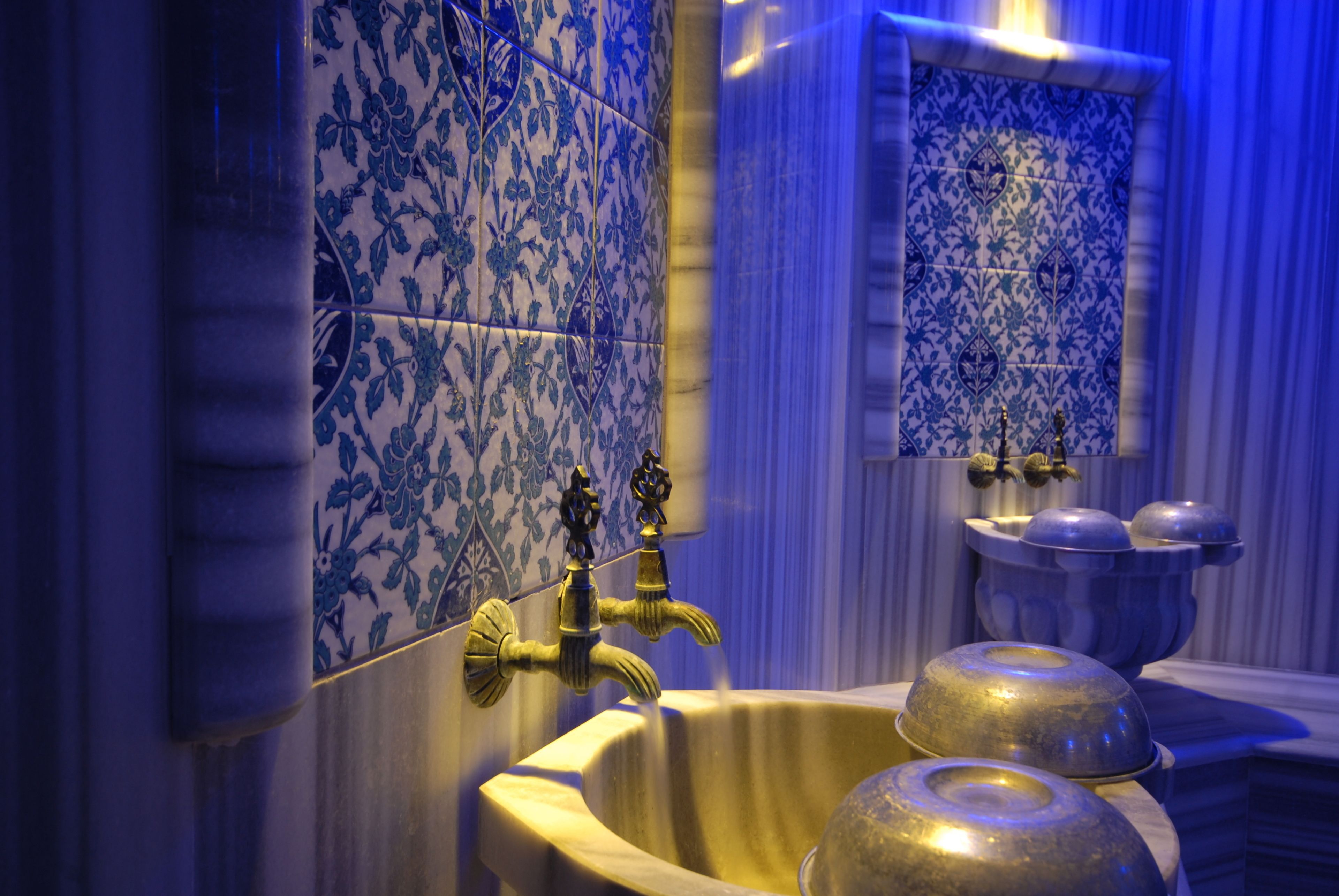A bathroom with blue and white patterned tiles, a gold faucet, and a sink with a gold basin.