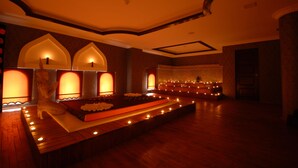 A dimly lit room with a long bench, arched alcoves, and a patterned carpet. - Suhan Cappadocia Hotel & Spa (Avanos)