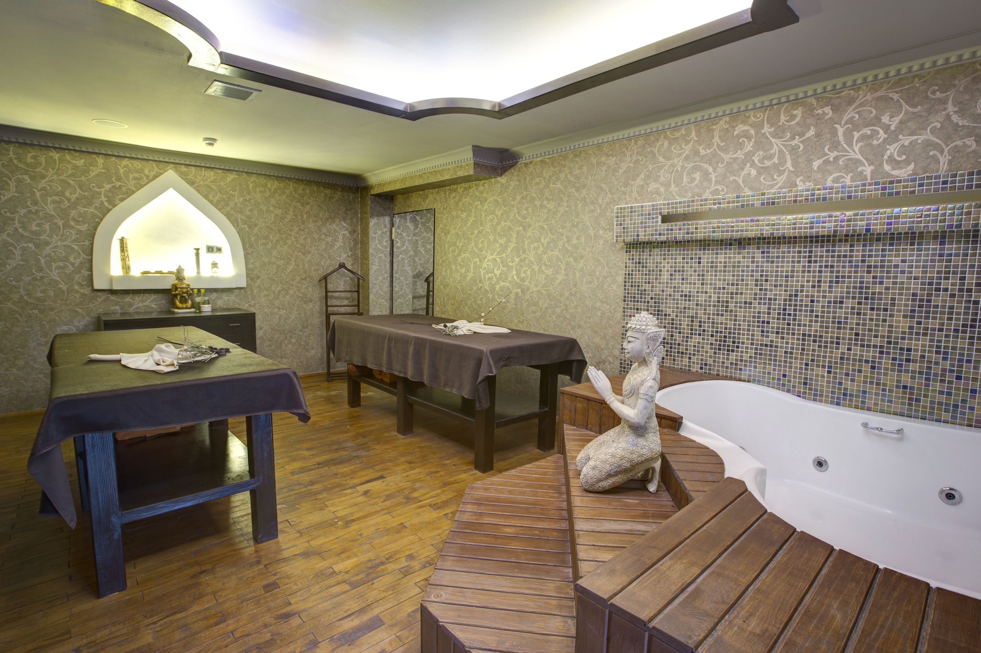 Un baño con piso de madera, una bañera, un tocador con espejo y una mesa con toalla.