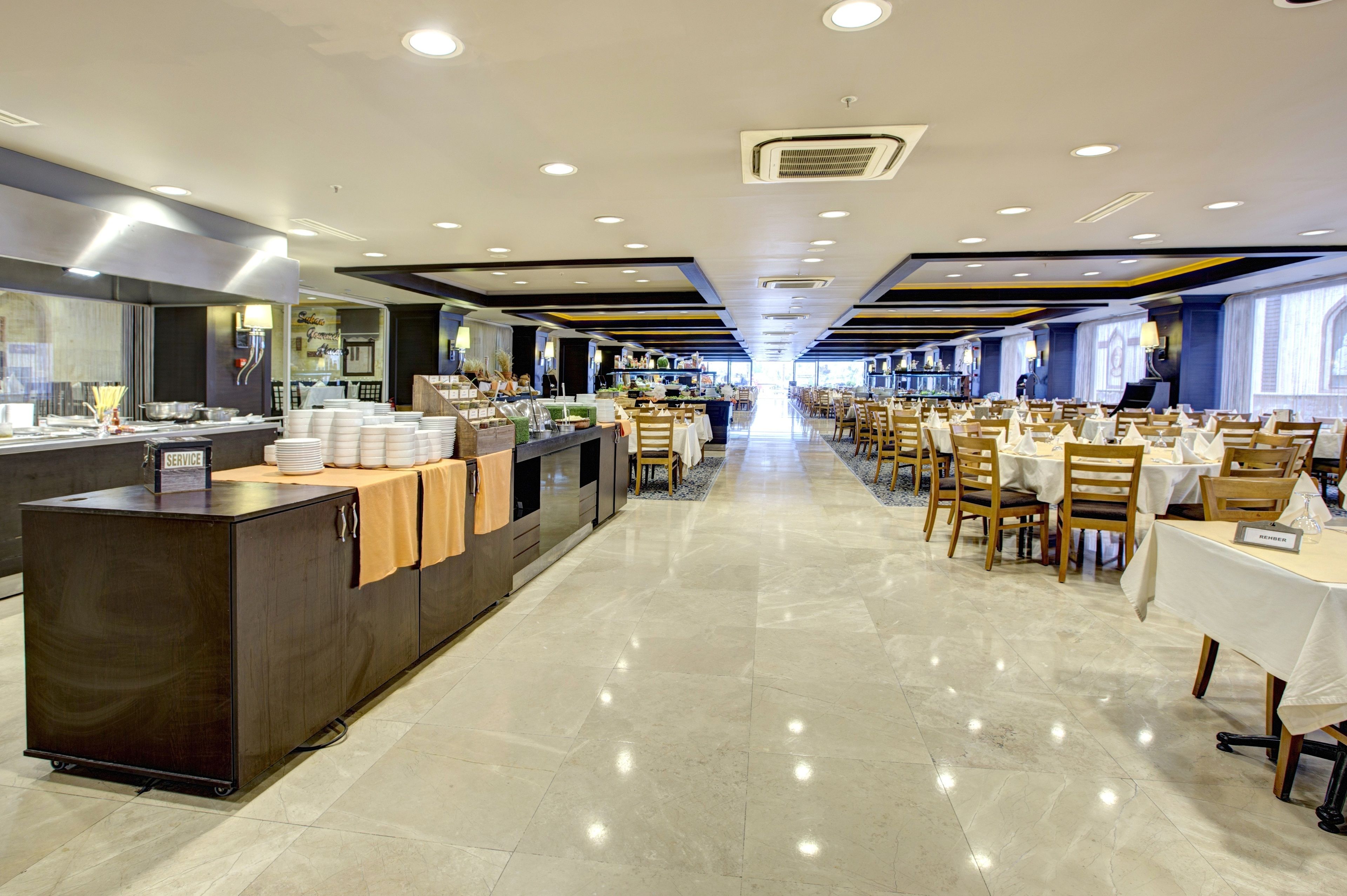 Un'ampia sala da pranzo di un hotel, con un lungo bancone, diversi tavoli e sedie.