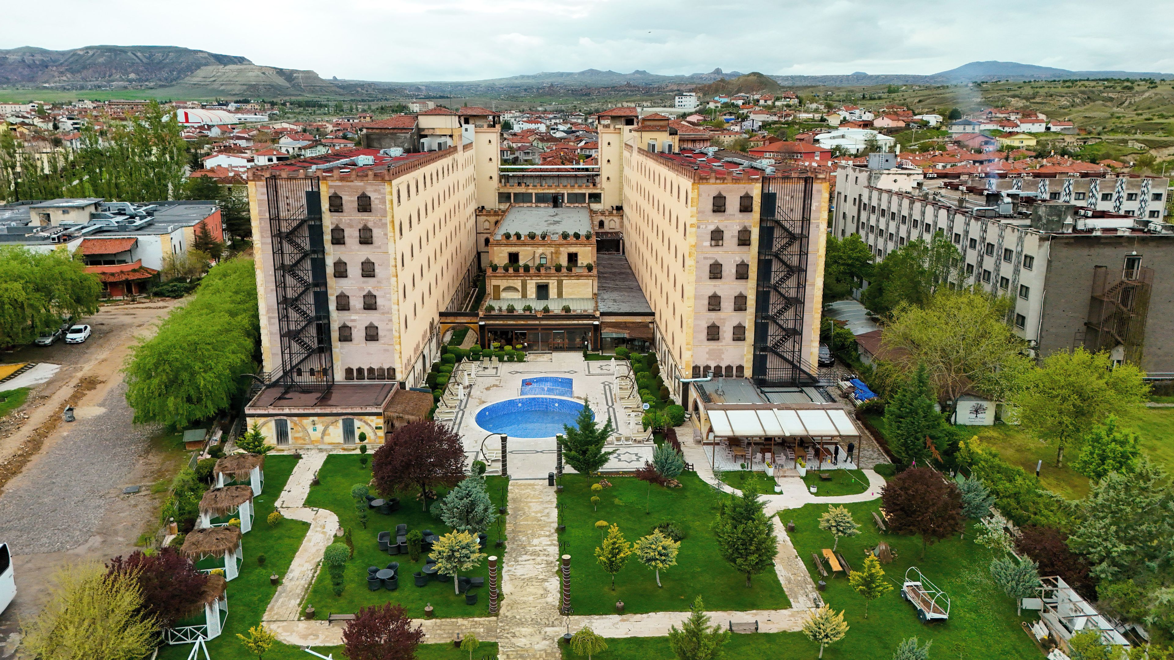 A hotel with a central courtyard, a swimming pool, and a view of the surrounding cityscape.