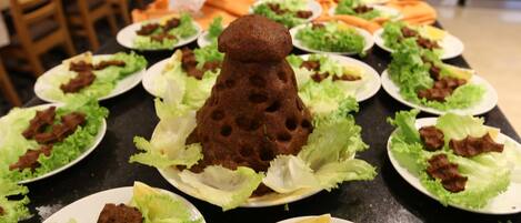 En buffet med tallerkener med mad, herunder salat og kød, samt en dekorativ midtpunkt.