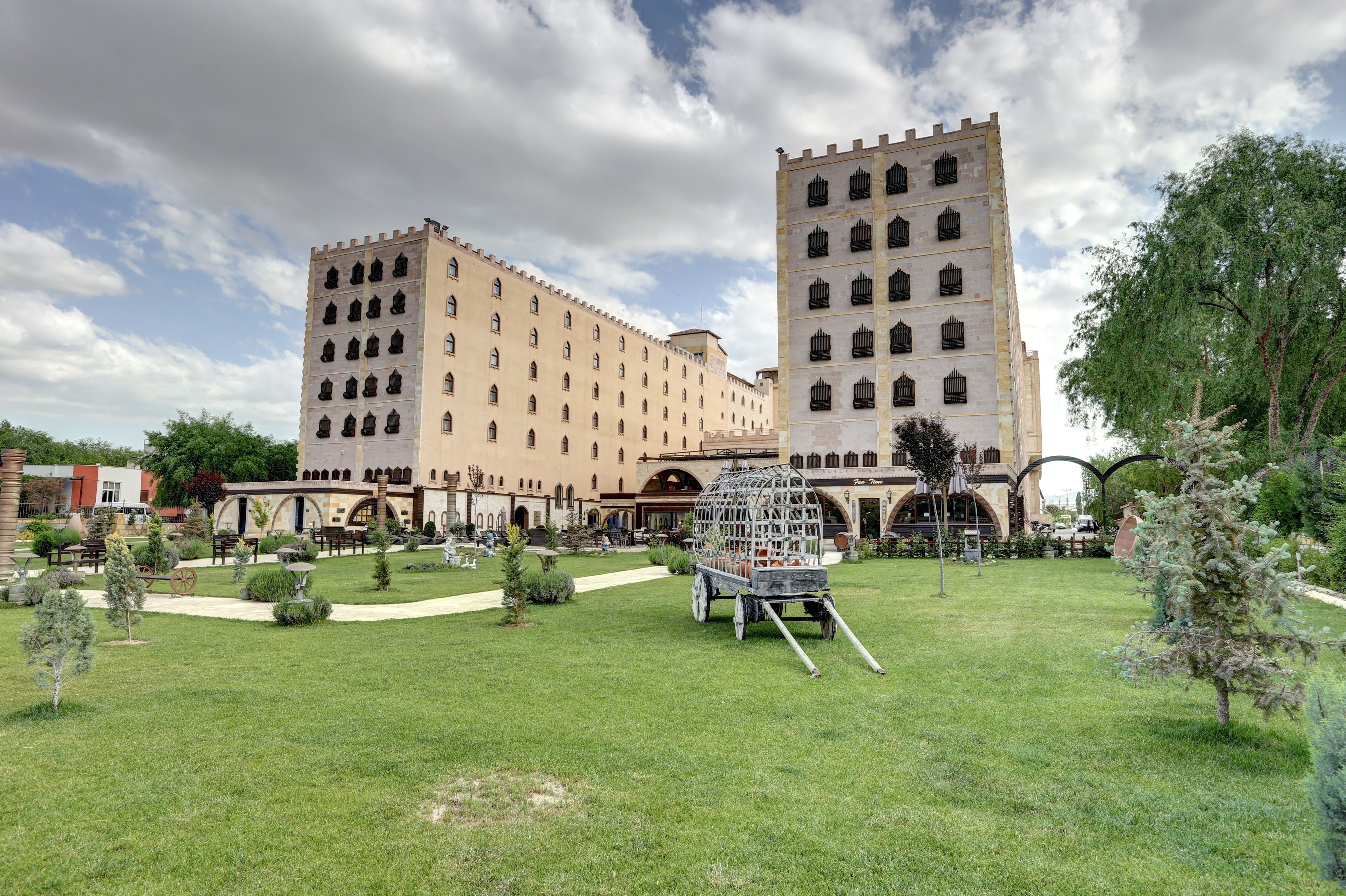 Un edificio grande con múltiples torres y un patio que incluye una escultura de jaula para pájaros.