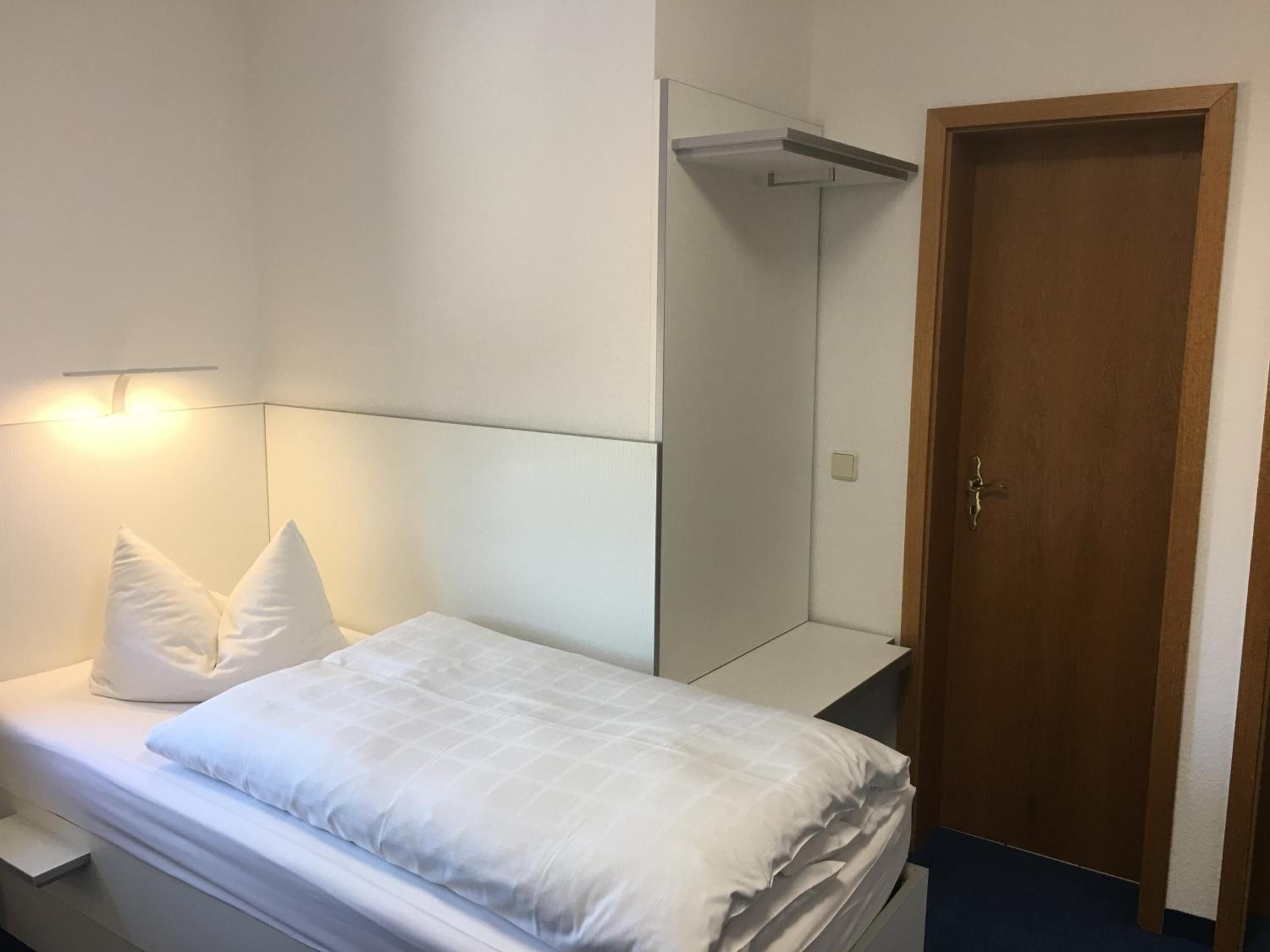 Ein Schlafzimmer mit einem Bett, einer Holztür und einem Spiegel.