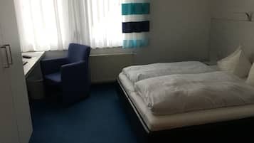 A hotel room with a bed, a desk, a chair, and a window with curtains.