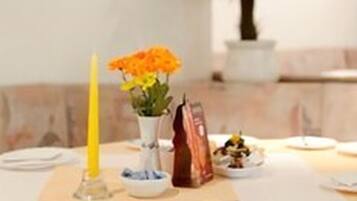 A dining table set with plates, a candle, and a vase with flowers.