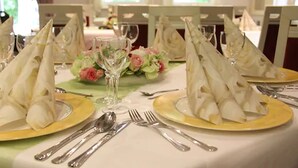A table set for a formal dining experience with neatly folded napkins, silverware, and a glass of water.