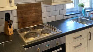 A modern kitchen with white cabinets, a stainless steel stove, and a window providing natural light. - Brinkburn Serviced Apartments (Darlington)