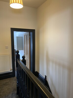 A staircase with a black handrail and a light fixture above. - Brinkburn Serviced Apartments (Darlington)