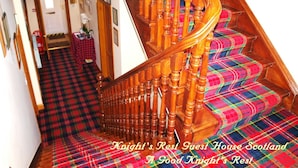 A staircase with wooden balusters and a plaid carpet.