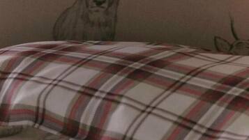 A bed with a plaid blanket and a wall with a deer head design.