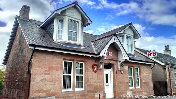 A traditional stone building with a gabled roof, two bay windows, and a prominent 'B&B' sign.