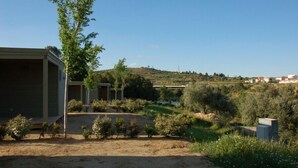 Ein Wohngebiet mit einem Haus, einem überdachten Außenbereich und einer hügeligen Landschaft im Hintergrund.