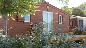 Eine Holzhütte mit Veranda, Schiebetür und kleiner Terrasse.