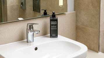 A modern bathroom with a white sink, a chrome faucet, and a bottle of press-to-impress body wash.