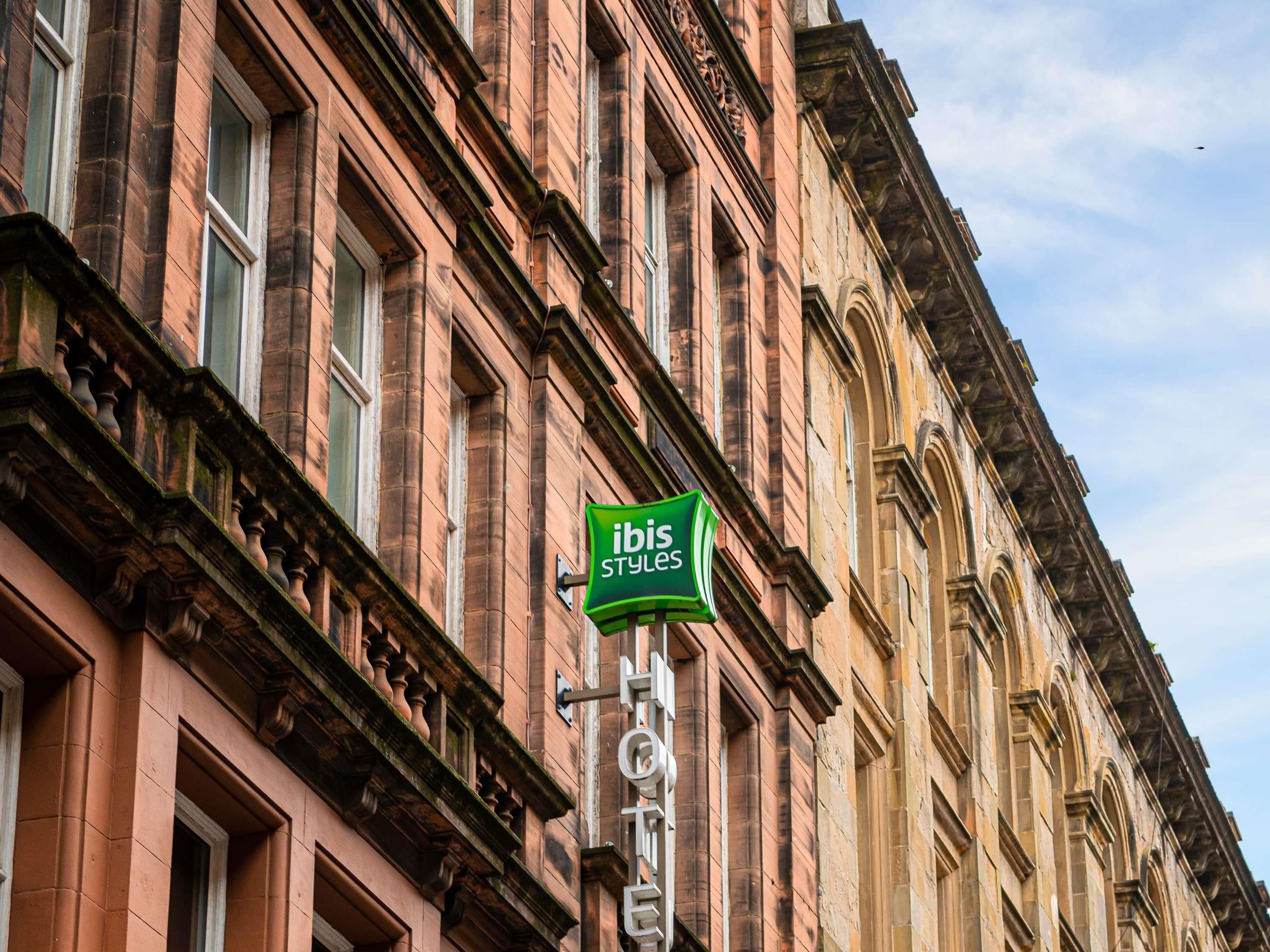 Un bâtiment historique avec une enseigne verte indiquant « hôtel ibis Styles ».