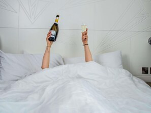 A person lying in bed with a bottle of champagne and a glass. - Ibis Styles Glasgow Centre George Square (Glasgow)