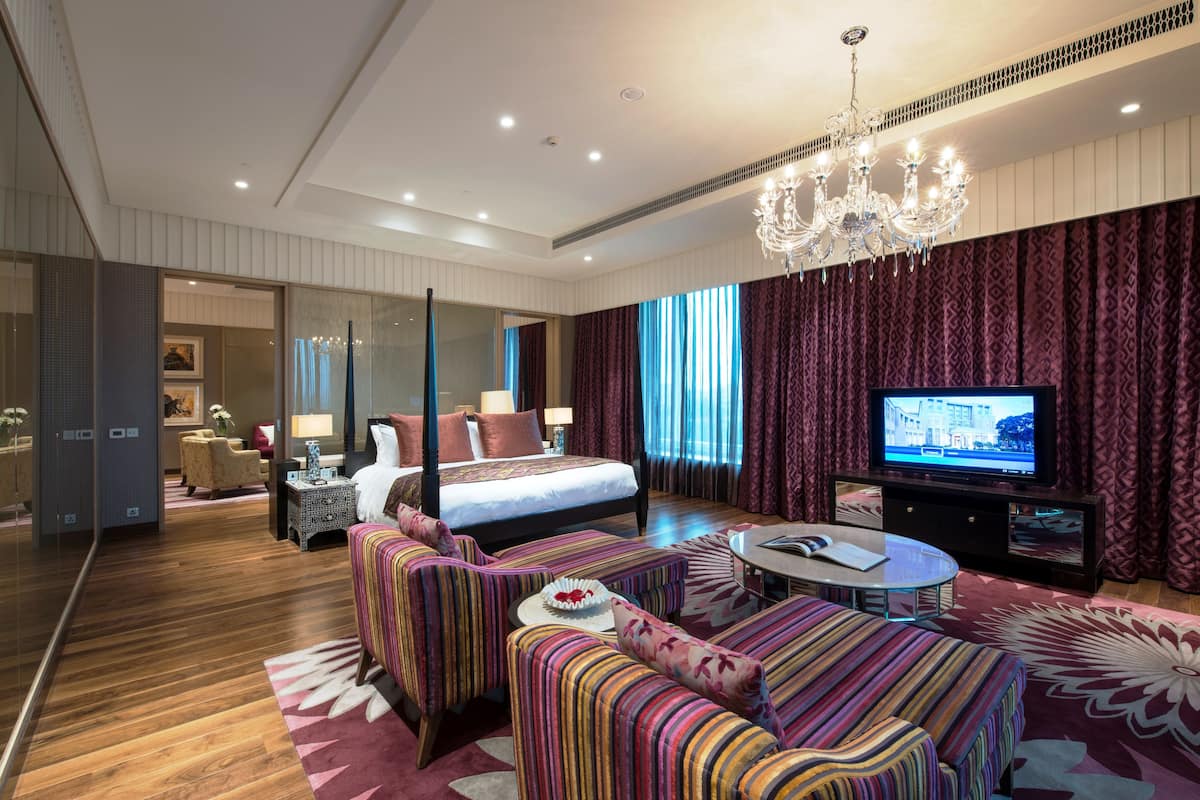 Una habitación de hotel moderna con una cama grande, televisión, sofá y candelabro.