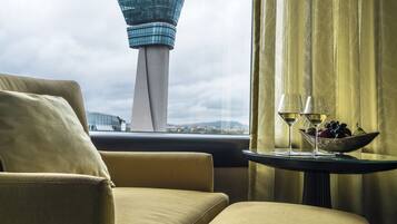 Quarto de hotel com vista para uma torre e uma mesa com uma tigela de frutas e copos.