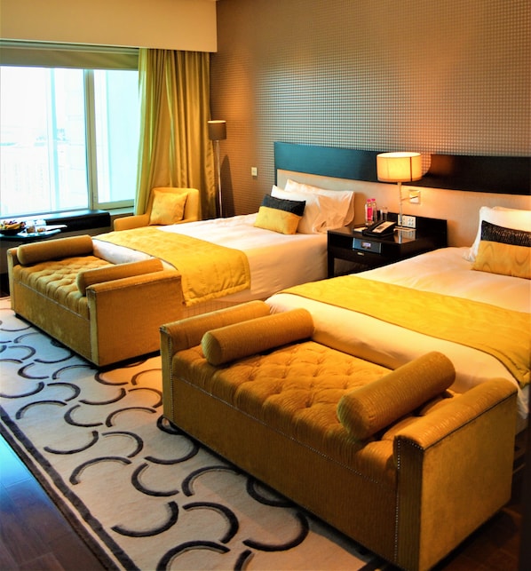 A hotel room with two beds, a sofa, a nightstand, and a window with curtains. - Taj Santacruz (Mumbai)