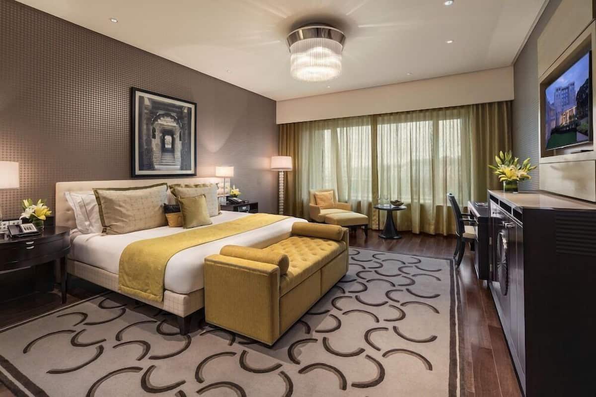 Habitación de hotel moderna con una cama grande, un escritorio, un televisor y vistas a la ciudad.