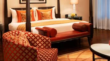 A hotel room with a bed, a chair, a table, and a lamp.