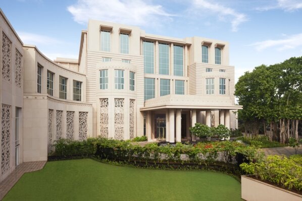 A large, modern building with a curved facade, large windows, and a well-maintained lawn. - Taj Santacruz (Mumbai)