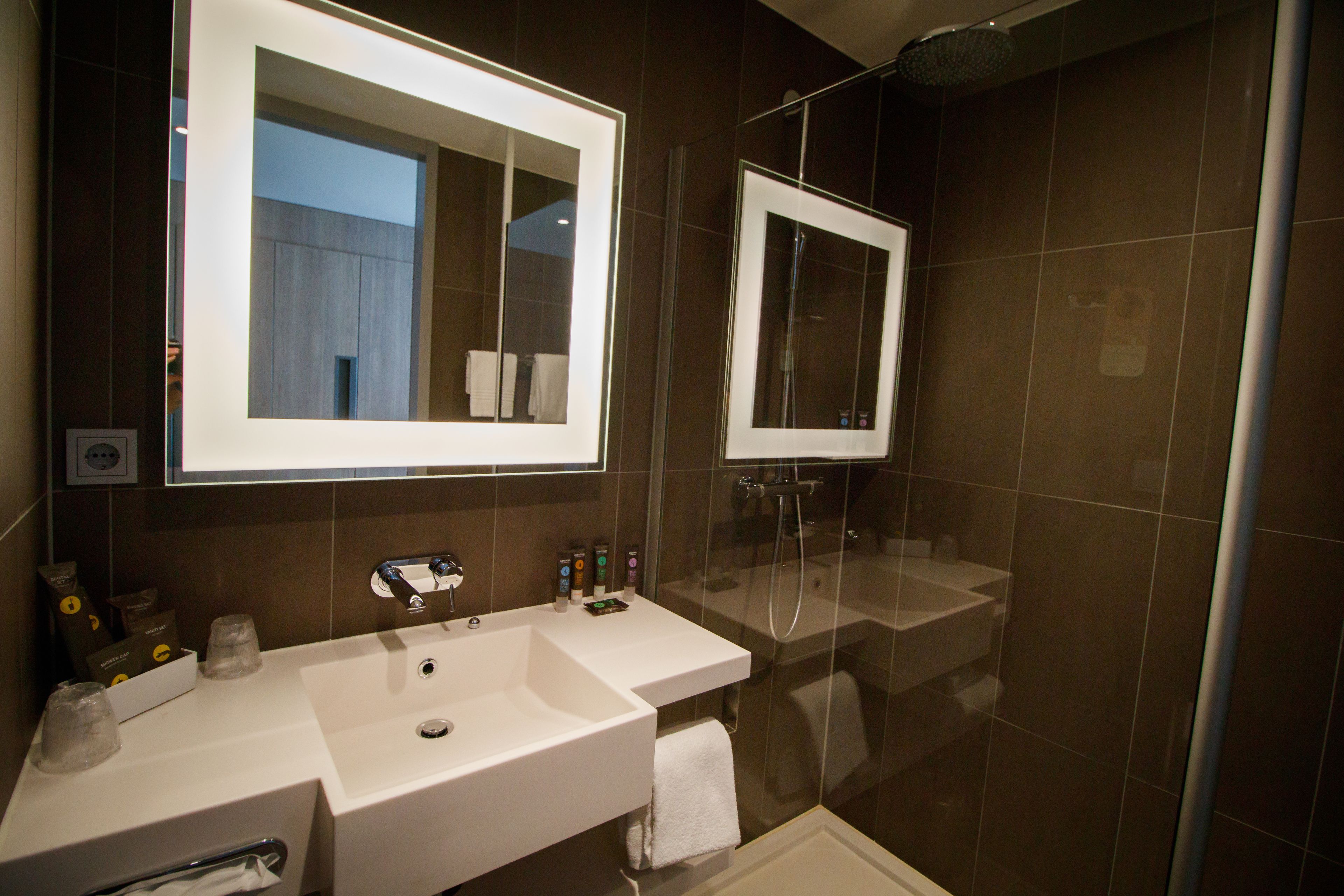 Un baño moderno con un espejo grande, un lavabo y una ducha.
