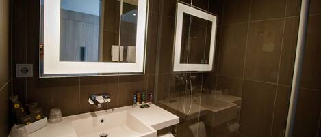 Un baño moderno con un espejo grande, un lavabo y una ducha.