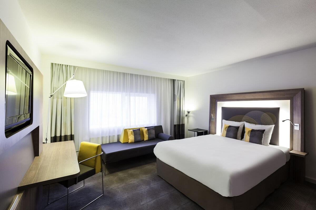 Una habitación de hotel con una cama grande, un sofá, un escritorio y un televisor.