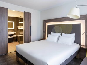 Hotellihuone, jossa on suuri sänky, kylpyhuone, jossa on peili ja pesuallas, sekä erillinen vaatehuone.