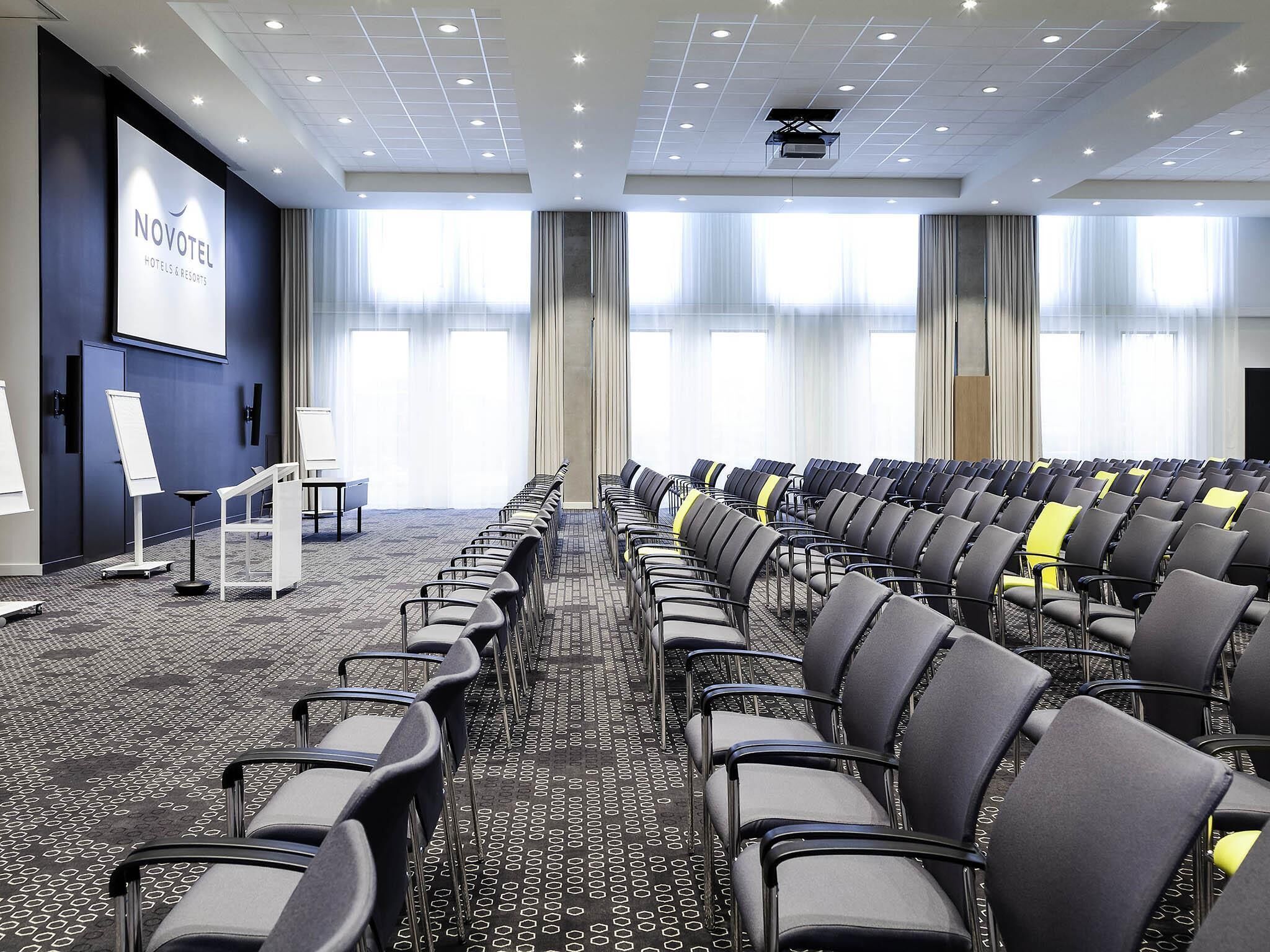A conference room with rows of chairs, a podium, and a projection screen.