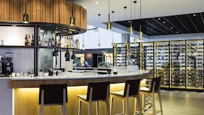 A modern bar area with a curved counter, bar stools, and a wine rack in the background.