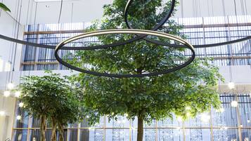 Een modern interieur met een centrale boom, zithoeken en een hoge plafond met hangende lampen.
