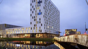 A modern hotel with a reflective pool in front, featuring a prominent 'NOVOTEL' sign.
