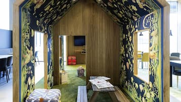 Een gezellige kamer met houten inrichting, een televisie, een klein tafeltje en een kleurrijk bloemenpatroon op de muur.