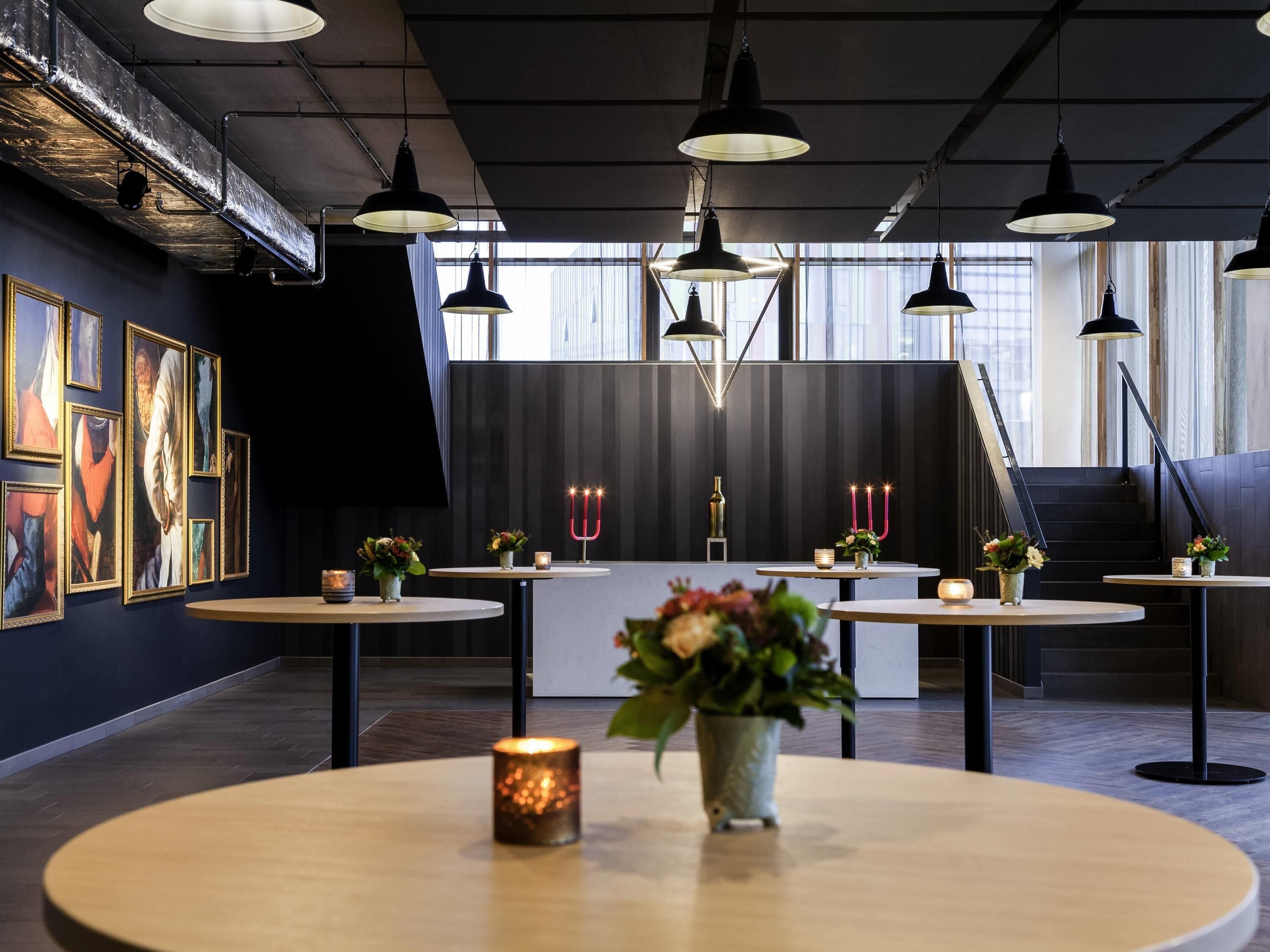 A modern interior with round tables, pendant lighting, and artwork on the walls.
