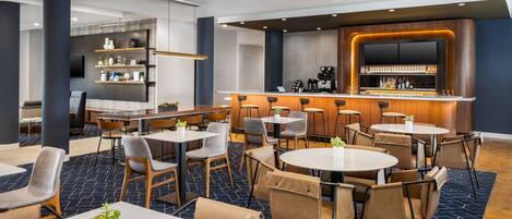 Eine moderne Hotelhalle mit Barbereich, Sitzgelegenheiten und einer Rezeption.