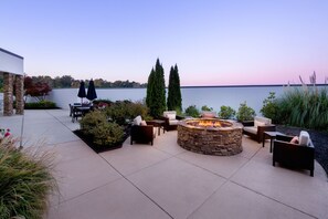 A patio area with a stone fire pit, outdoor furniture, and a view of a lake. - Courtyard by Marriott Auburn (Auburn)