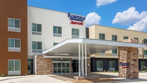 A Fairfield Inn & Suites Marriott hotel with a modern design, featuring a covered entrance and a brick pillar with the hotel name.