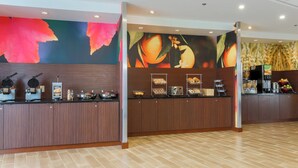 A modern breakfast bar with waffle makers, a coffee station, and a fruit display.