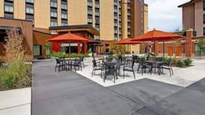 A hotel courtyard with outdoor seating and a large building in the background. - Homewood Suites by Hilton Seattle-Issaquah (Issaquah)