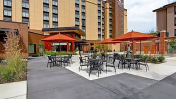 A hotel courtyard with outdoor seating and a large building in the background.