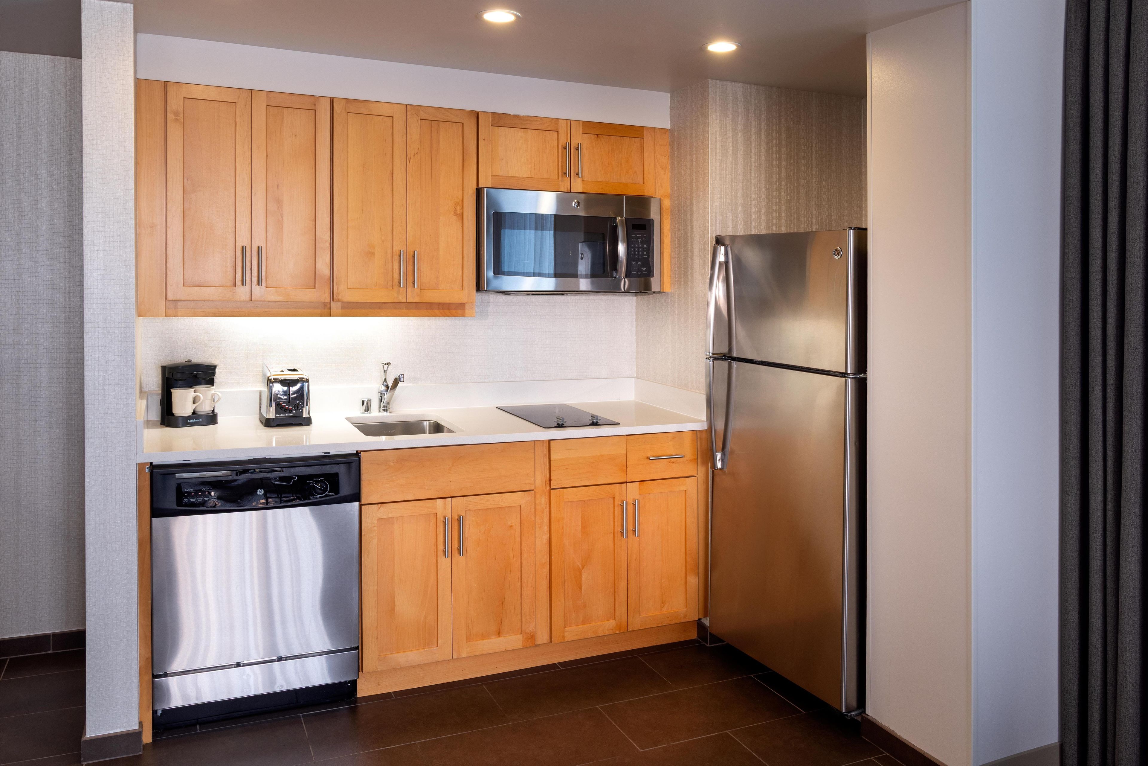 A modern kitchen with wooden cabinets, stainless steel appliances, and a dishwasher.