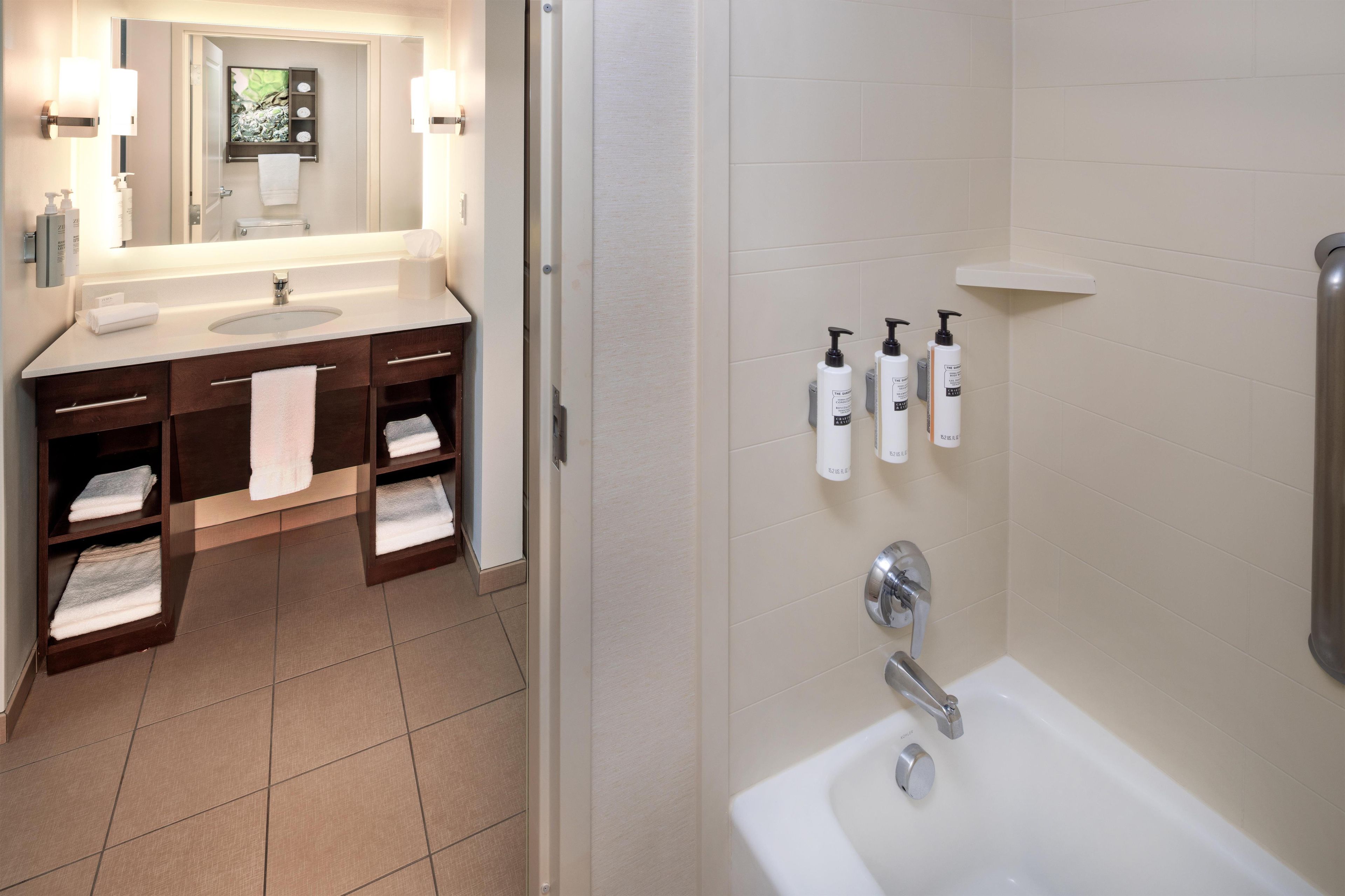 A modern bathroom with a sink, mirror, towel rack, and a shower area.