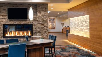 A modern interior with a stone wall, a fireplace, a flat-screen TV, and a reception desk.