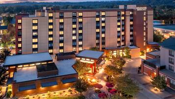 Un hotel de varios pisos con techo plano, zona de estar al aire libre y vistas a un área boscosa.