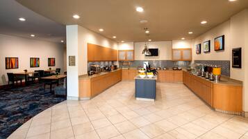 A spacious kitchen with a central island, wooden cabinets, and a tiled floor.