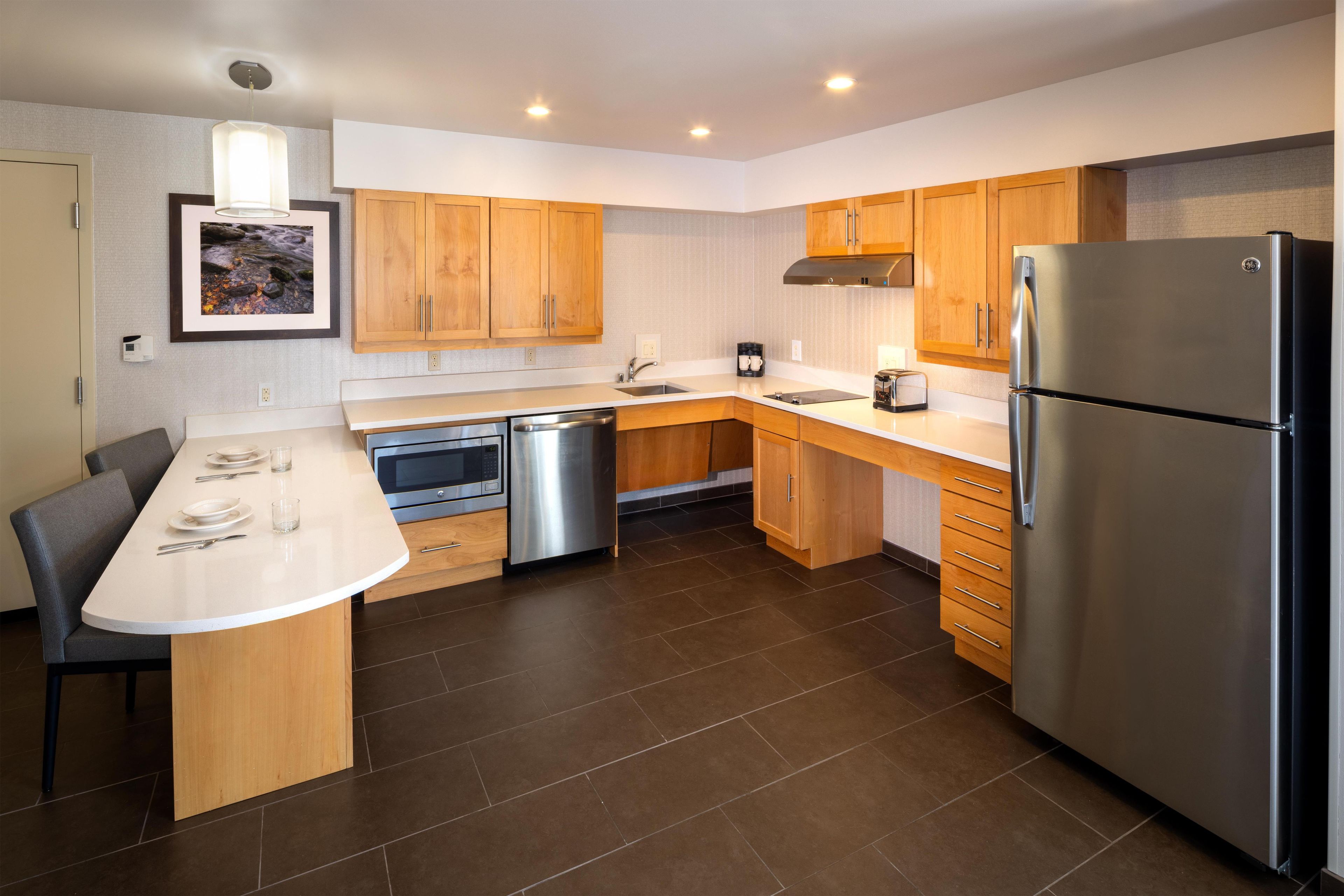A modern kitchen with wooden cabinets, stainless steel appliances, and a dining area with a white table and chairs.